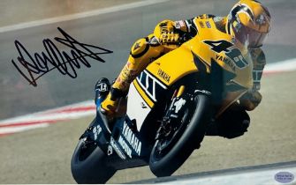 Framed signed Valentino Rossi picture. Rossi pictured cornering on his yellow Yamaha motorbike.