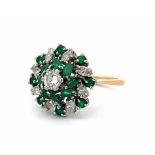 An 18ct and platinum emerald and diamond cluster ring. The principal diamond estimated at 0.36ct
