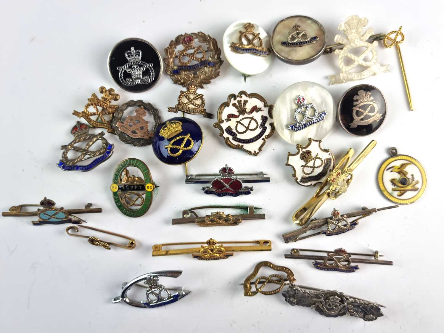 A collection of military brooches and shoulder titles etc. to include a 9ct gold bar brooch, silver,