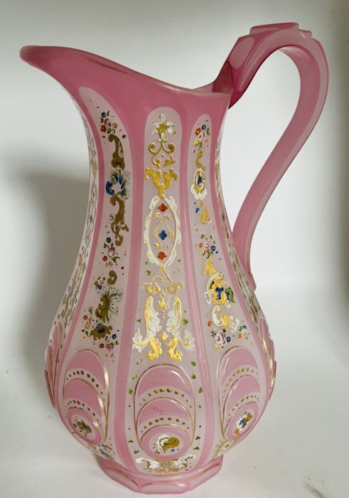 A late 19th century pink tinted glass jug with opaque panels enamelled with stylised foliate