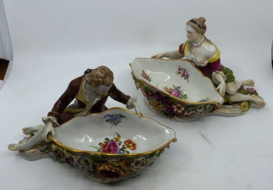 A pair of Continental porcelain figural sweetmeat dishes modelled as reclining male and female