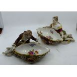 A pair of Continental porcelain figural sweetmeat dishes modelled as reclining male and female