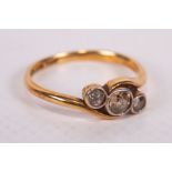 An early 20th century diamond set crossover ring in yellow metal stamped 18ct and Plat. The