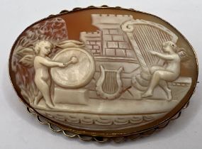 A 9ct stamped oval shell cameo brooch, carved to depict putti with drum and harp. Approximate gross