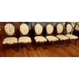 A set of six Victorian upholstered walnut dining chairs, the oval backs surmounted by carved