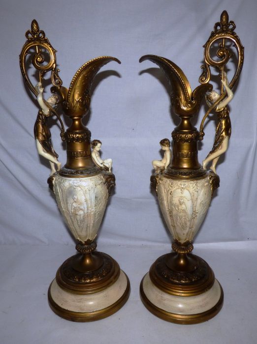 A pair of late 19th century gilt and cream finished spelter Renaissance style ewers, cast with