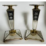 A pair of brass and etched mirror glass candlesticks, the glass engraved with musical trophies and