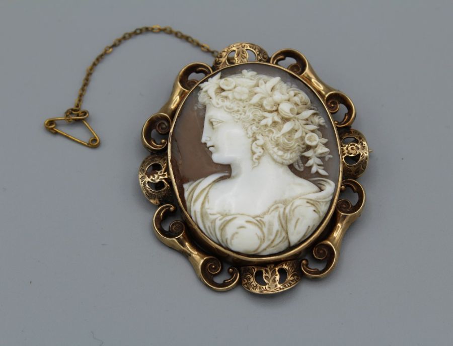 A shell cameo brooch, with a substantial scrollwork mount in yellow metal, featuring a left facing