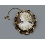 A shell cameo brooch, with a substantial scrollwork mount in yellow metal, featuring a left facing