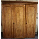 A Victorian mahogany triple wardrobe / press, the moulded cornice over three arched panel doors