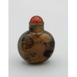 Snuff bottle. Chalcedony of compressed rounded form resting on a small oval foot, carved in low
