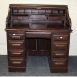 An early 20th century oak roll top desk, the fall enclosing a fitted interior raised on a pair of