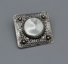 An Arts and Crafts brooch in a square shape and set with a mabe pearl/mother of pearl, bezel set