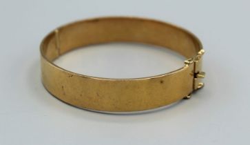A substantial yellow metal hinged bangle, with a box clasp and double safety latches, gross weight