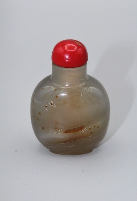 Snuff Bottle. Chalcedony of rounded form with a footrim, lightly carved, using the darker tone areas