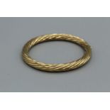 A hinged 9ct gold bangle in twisted form. Hinge and clasp in good condition, gross weight