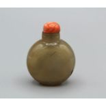 Snuff bottle. Chalcedony of flattened round shape on a small raised footrim, carved with a boy