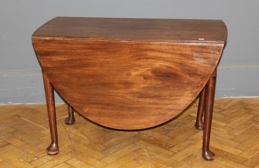 A George III walnut gateleg table, the oval flaptop raised on turned tapered legs and pad feet,