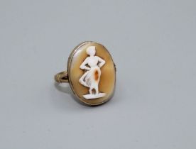 A shell cameo ring depicting the figure of a standing woman, in classical period dress. Size J.