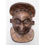 A 20th century carved wood African tribal mask with pursed mouth, lozenge pattern headdress and