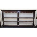 A mid 18th century oak delft rack, the moulded cornice over serpentine frieze and three open