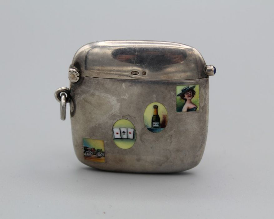 A sterling silver vesta, with small enamel panels depicting racing cars, playing cards, champagne