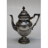 A Middle Eastern white metal teapot of demi-reeded Neo Classical form with angular handle, on a