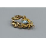 An aquamarine set laurel spray brooch in 9ct gold hallmarked setting, as found due to split in the