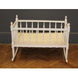 An Edwardian white painted rocking cradle with spindle turned splats and sledge feet, 68 x 60 x