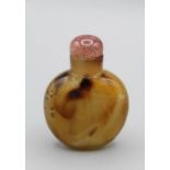 Snuff Bottle. Chalcedony of compressed ovoid form resting on a small oval base, the darker