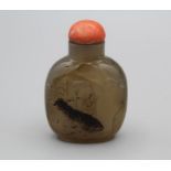 Snuff bottle. Chalcedony of rounded rectangular form on a broad footrim, carved using the darker