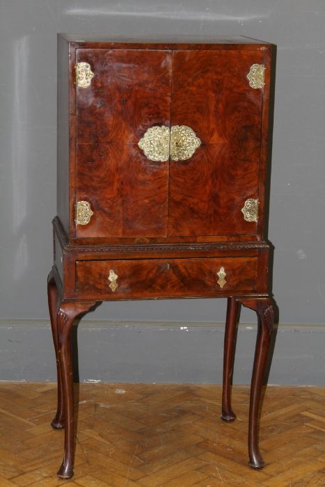 An Edwardian figured walnut cabinet on stand, the pair of doors with ornate brass furniture
