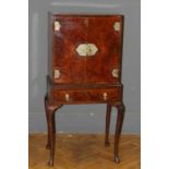 An Edwardian figured walnut cabinet on stand, the pair of doors with ornate brass furniture