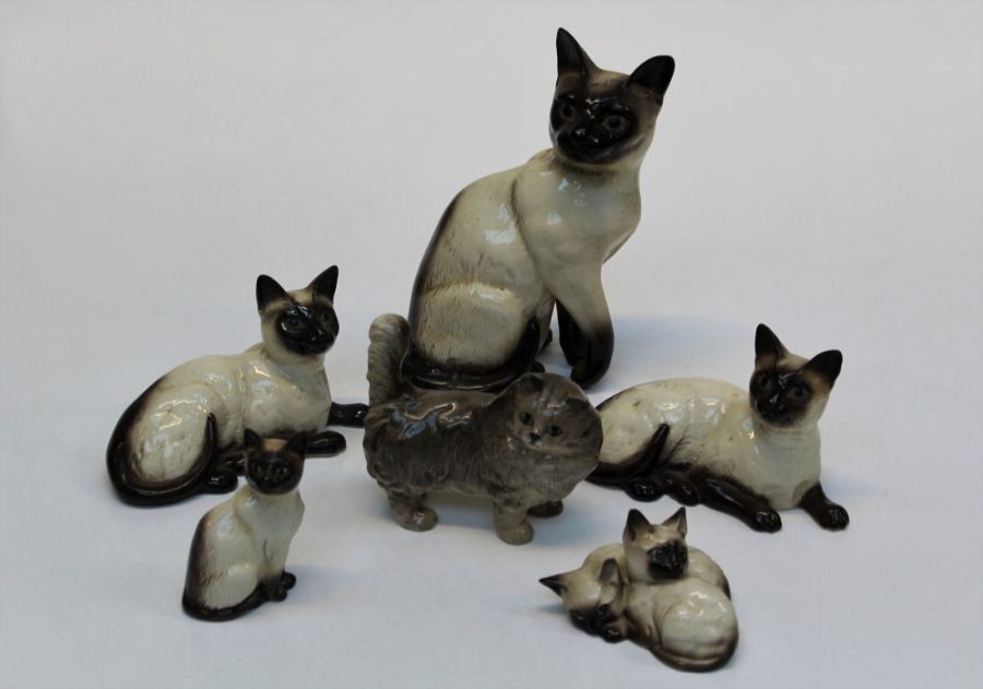 A group of five Beswick figures of Siamese cats comprising one seated head forward H24cm, two