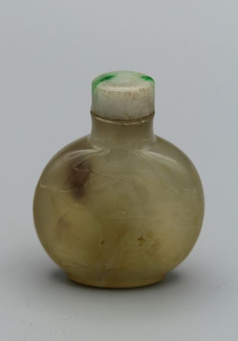 Snuff Bottle. Chalcedony of compressed round form on a raised footrim, carved in low relief with two