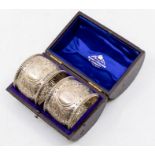 A pair of Victorian silver napkin rings, profuse scrolling foliate and floral decoration, central