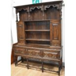 A reproduction solid oak Jacobean style kitchen dresser with three plate racks, flanked by two spice