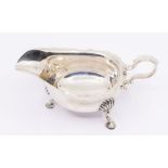 A Georgian style silver sauceboat, wavy rim on three shell and hoof feet, hallmarked by Thomas