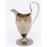 A George III iilver helmet shaped cream jug with bright cut decoration on a circular base.