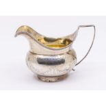 A George III silver baluster/helmet shaped cream jug with bright cut engraved foliate decoration,