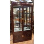 A reproduction Chinese style display cabinet, having glazed front and sides, staggered glazed