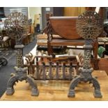 A 17th Century cast iron fire grate and dogs with circular, pierced ornate tops on arched legs with