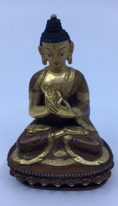 A 20th century Sino-Tibetan gilt and polychrome painted bronze figure of seated Buddha with hands in