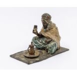 Franz Bergmann (1861-1933): A Viennese cold painted bronze model of a Moor seated on a carpet,