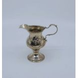 A George III silver cream jug, London 1780, makers' mark indistinct, repouse flowers and garlands,