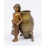 An Austrian bronze modelled as a boy gathering water resting by a large urn, the urn with supporting