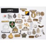 An assortment of British cap badges, buckles, shoulder titles and cloth badges, including a Royal