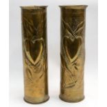 A pair of 75 mm WWI era brass shell casings, both with stipple and repousse decoration of hearts and