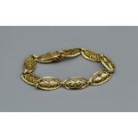 A filigree panel bracelet in yellow metal bearing French marks, tested as 18carat gold