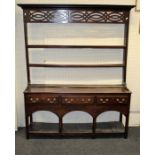 A 19th century Welsh oak dresser, the mounted cornice over an open plate rack, having three